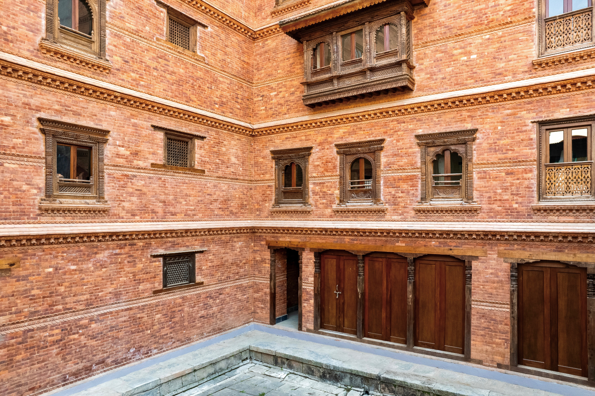 Traditional Newa courtyard with carved walnut windows and raked gravel